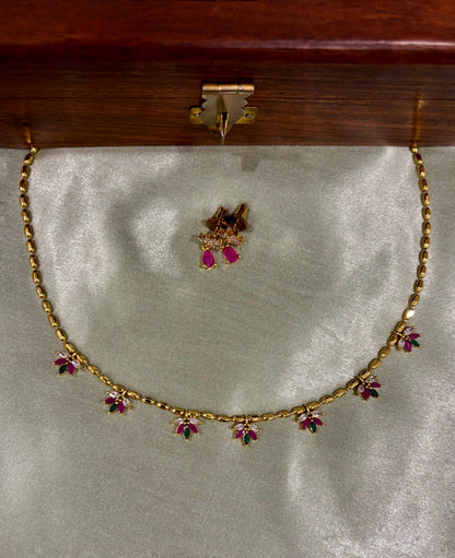 Gold necklace with floral gemstone accents and matching earrings on satin fabric