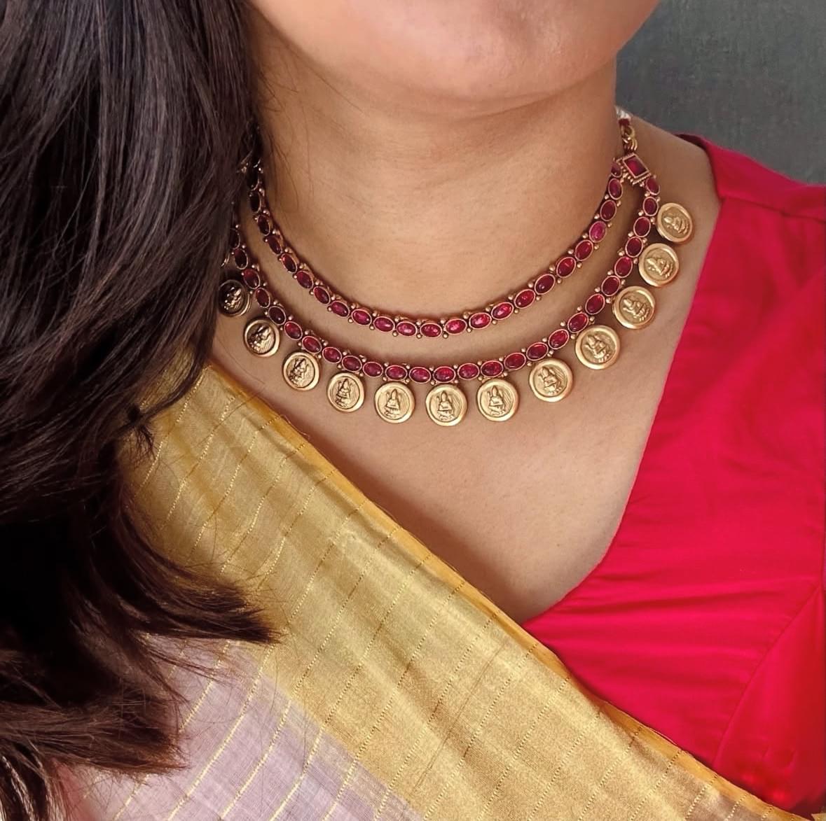 Elegant South Indian temple necklace with red kemp stones and gold coin motifs, paired with a silk saree.