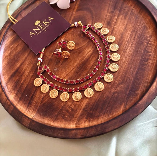 South Indian temple jewellery set with red stones and gold coins, displayed on wooden tray