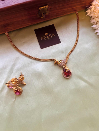 Elegant South Indian bird-themed necklace and earrings with red gemstones, perfect for bridal wear.