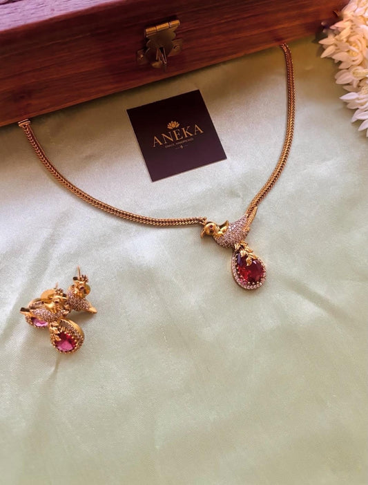 Elegant South Indian bird-themed necklace and earrings with red gemstones, perfect for bridal wear.