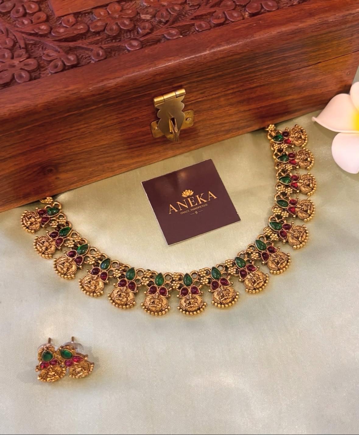 South Indian temple jewellery set with green and red stones, displayed on silk with wooden box