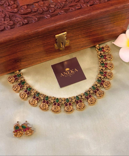 South Indian temple jewellery set with green and red stones, displayed on silk with wooden box