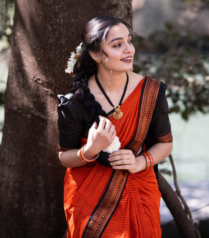 Woman in orange saree with temple jewellery and floral hair accessory